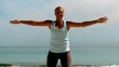 Sportswoman doing jumping jacks on the beach