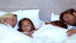 Family sleeping together in bed