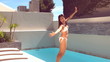 Pretty woman jumping into swimming pool