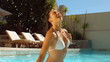 Attractive woman in swimming pool tossing her wet hair 