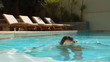 Attractive woman dipping her head into swimming pool