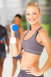 young fit woman lifting dumbbell