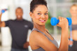 fit african woman lifting dumbbell