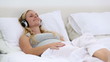 Blonde woman enjoying listening to music on bed