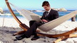 Businessman typing on his laptop in a hammock