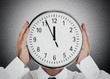Businessman hiding his face with clock
