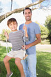 Portrait of  happy father pushing son on a swing