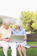 Elderly couple using a laptop in the park