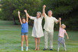 Smiling grandparents standing with their grandchildren cheering