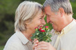 Older couple looking at each other and holding flowers