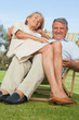 Older woman sitting on lap of smiling partner sitting in deck chair