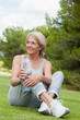 Happy mature woman in sportswear drinking water