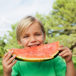 Cute blonde boy eating watermelon