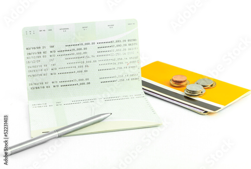 Photo: Coins and pen on account passbook isolate Coins and pen on account passbook isolate