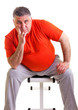 Overweight man sitting on a bench for abdominals, he takes a bre