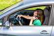 Young woman with hand on steering wheel using mobile phone