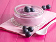 Joghurt mit Heidelbeeren auf einem Holztablett.