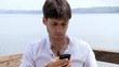 Handsome business man texting with phone on a lake