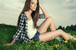Portrait of young beautiful brunette woman  sitting on grass