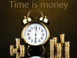 Alarm clock with coins on dark background