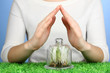 Hands protect grass under glass cover