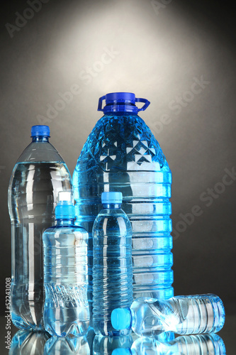Photo: Different water bottles on grey background Different water bottles on grey background