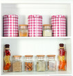 Beautiful white shelves with spices in glass bottles