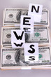 White paper cubes labeled "News" with money on grey background