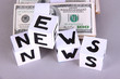 White paper cubes labeled "News" with money on grey background