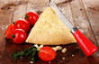 Piece of Parmesan cheese with knife on wooden table close-up