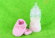 Bottle for milk and booties on towel background