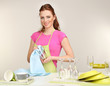 Beautiful young woman wipes clean utensils in kitchen