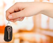Key with leather trinket in hand on bright background