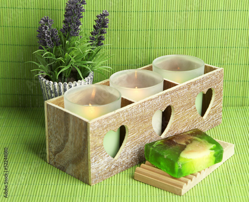 Photo: Candles in wooden candlestick, lavender and soap, on green mat Candles in wooden candlestick, lavender and soap, on green mat