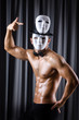 Muscular actor with mask against curtain