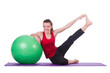 Young woman with ball exercising on white