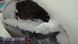 Car in snow, woman cleans snow from car