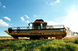Yellow harvester combine on field harvesting gold wheat