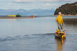 man pulling empty kayak across shallow water