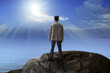 Photo: young man standing on rock mountain and looking to the sun young man standing on rock mountain and looking to the sun