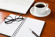 Laptop with cup of coffee and notepad on wooden background