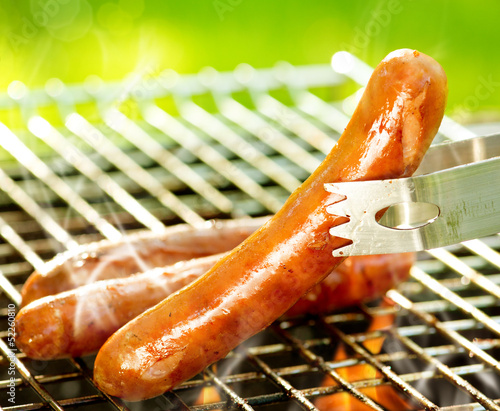 Photo: Grilled Sausage on the flaming Grill. BBQ. Bearbeque outdoors Grilled Sausage on the flaming Grill. BBQ. Bearbeque outdoors