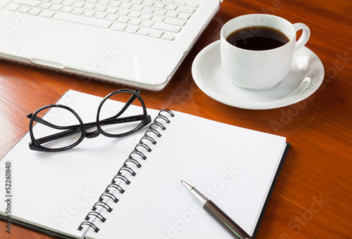 Photo: Laptop with cup of coffee and notepad on wooden background Laptop with cup of coffee and notepad on wooden background