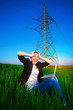 businesswoman in a green field with a laptop. power lines