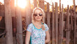 Beautiful blonde girl with a scythe is standing at the fence