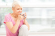 Smiling woman with mug sitting at home while smiling