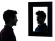 man serious in front of his mirror silhouette