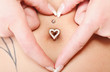 hands heart symbol around navel piercing