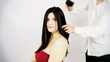 Hairdresser brushing long hair of beautiful woman