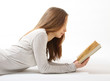 Lying girl with a book on white background